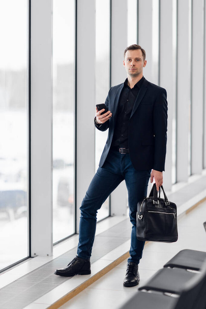 Business man using mobile phone app in airport. Young business professional man texting smartphone walking inside office building or airport terminal. Handsome man wearing stylish suit jacket indoors. - Foto, Bild