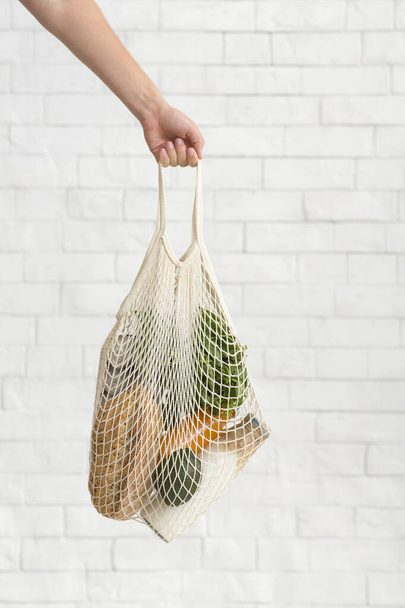 Az ökohálós bevásárlótáskát ökozöldségekkel szállító nő - Fotó, kép