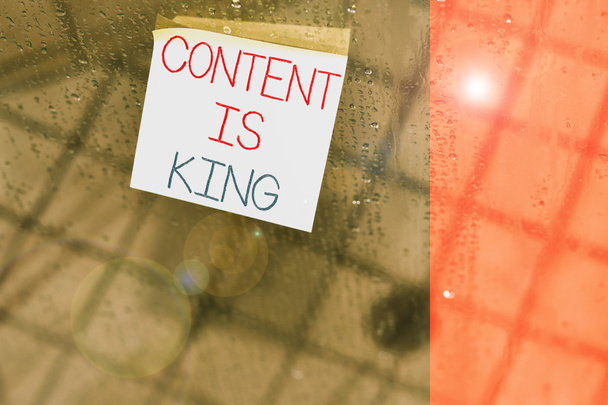 Pisząc notatkę pokazującą Content Is King. Biznes photo showcasing Content is the heart of todays marketing strategies Kwadratowy kawałek papieru notacja trzymać się teksturowane szklane okno. - Zdjęcie, obraz
