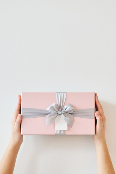 Una chica sostiene una caja de regalo sobre un fondo blanco
.  - Foto, Imagen