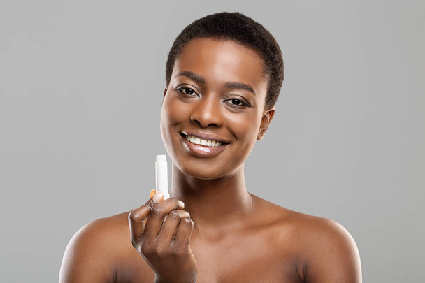 Portrait of beautiful black woman holding hygienic lip balm - Zdjęcie, obraz