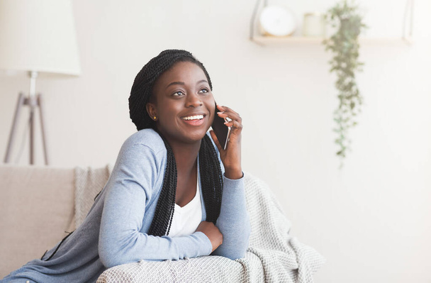 Nuori musta nainen puhuu kännykällä ystävän kanssa kotona
 - Valokuva, kuva