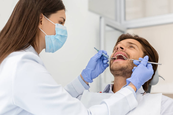 Diş sağlığı kliniğinde hasta kontrolü yapan bir adam. - Fotoğraf, Görsel