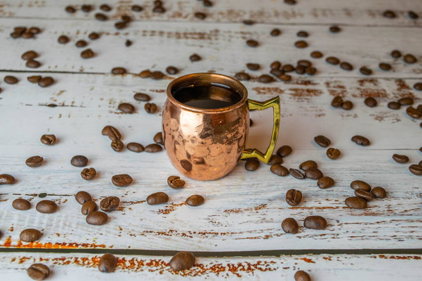tazza di rame con espresso su tavolo di legno bianco con chicchi di caffè biologici
 - Foto, immagini