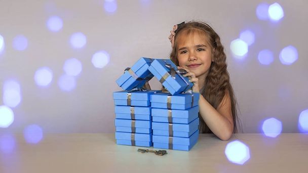 Jolie fille près de boîtes-cadeaux bleues formées comme une maison
 - Photo, image