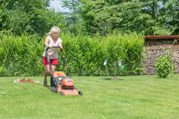 女は庭で草を刈る - 写真・画像