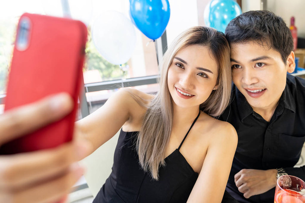 Young asian adult couple make selfie photographing for celebrating New Year and Christmas holiday together in living room of big apartment in big city. - Valokuva, kuva