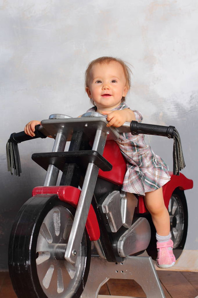 Chica motociclista sentada en una motocicleta de juguete
 - Foto, imagen