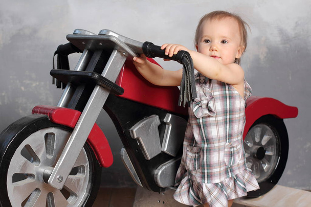 Little girl playing with a red toy motorcycle. - Foto, Imagen