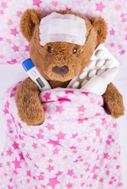 άρρωστος αρκουδάκι, τυλιγμένο σε επιδέσμους με θερμόμετρο μασχάλης - Φωτογραφία, εικόνα