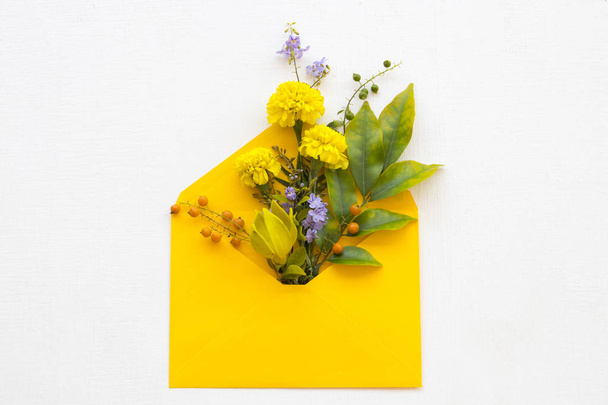 yellow flower marigold ,ylang ylang ,purple flowers and leaf arrangement flat lay postcard style in yellow envelope on background white  - Photo, Image