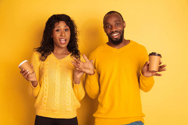 Young emotional african-american man and woman on yellow background - Foto, imagen