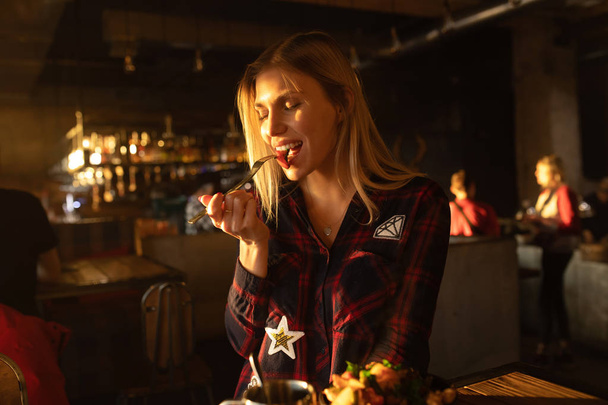 Positive woman eating salad at cozy cafe. - Photo, Image