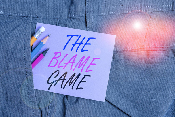 Writing note showing The Blame Game. Business photo showcasing A situation when showing attempt to blame one another Writing equipment and purple note paper inside pocket of trousers. - 写真・画像