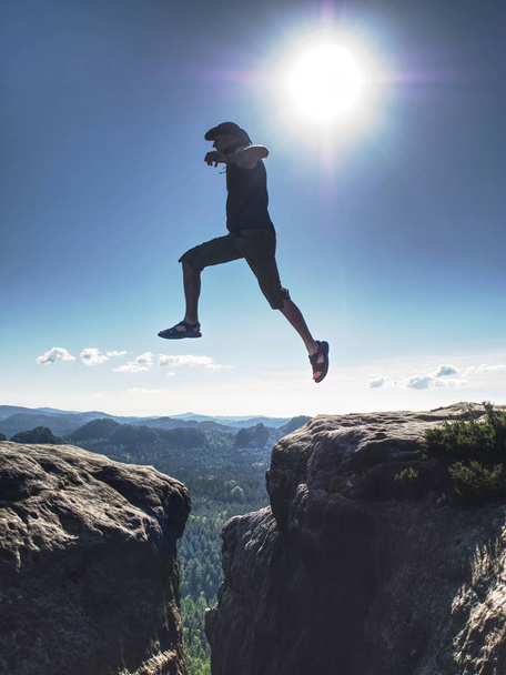 Springen tegen Sun. Springt over klif. Man op pad door rotsen / J - Foto, afbeelding