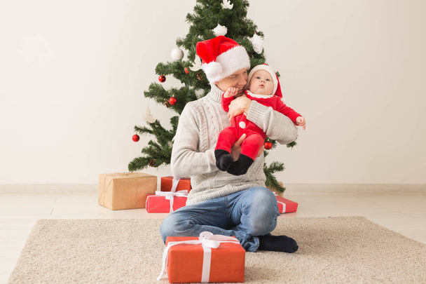 Padre con su bebé vistiendo sombreros de Santa celebrando la Navidad
. - Foto, Imagen