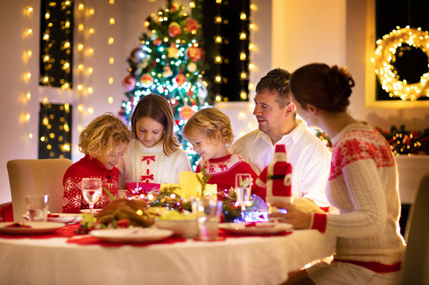 Çocuklu bir aile Noel yemeğini ağaçta yiyor. - Fotoğraf, Görsel
