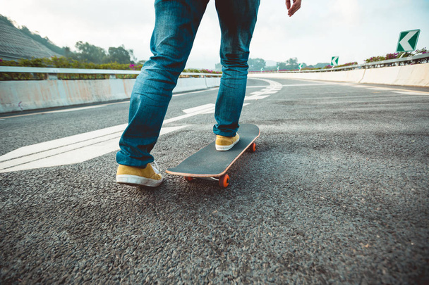 Skateboarder riding board on city street asphalt - Fotoğraf, Görsel