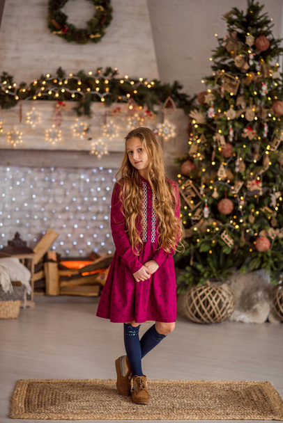 クリスマスツリーの近くの女の子。美しい子供はクリスマスツリーを飾る。髪の長い女の子の肖像画 - 写真・画像