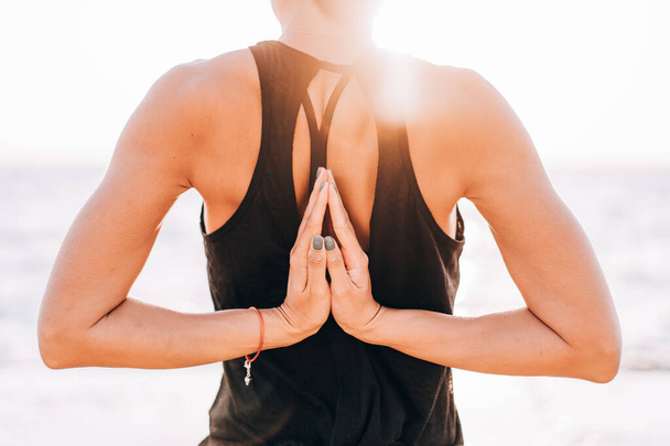 Unrecognizable woman makes greeting to the sun at sunrise. Hands in back namaste. Yoga, meditation, gratitude, healthy lifestyle concept. - Fotó, kép