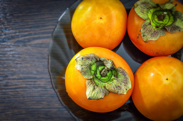 The horizontal photo in the center shows a fresh juicy persimmon on a glass plate - Foto, afbeelding