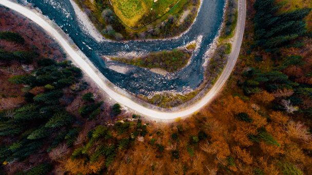 Θέα από ένα drone στο ποτάμι, δρόμο και φθινόπωρο δάσος στα Καρπάθια βουνά. - Φωτογραφία, εικόνα