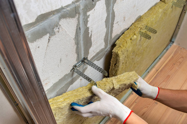 Trabalhador isolando uma parede da sala com minerais de lã de rocha termal ins
 - Foto, Imagem