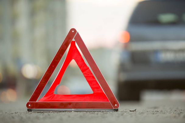 Червоний аварійний трикутник знак зупинки і розбитий автомобіль на міській вулиці
 - Фото, зображення
