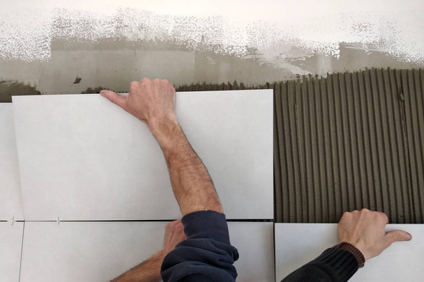 Werknemer handen putting keramische tegels op de muur. - Foto, afbeelding