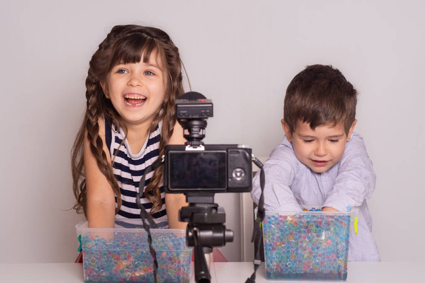 Милые маленькие видео блоггеры записывают видео на белом фоне. Детский блог
. - Фото, изображение