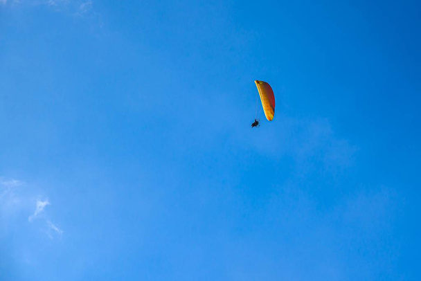  Το αλεξίπτωτο πλαγιάς πετάει πάνω από τα ψηλά βουνά. Αλεξίπτωτο πλαγιάς σε όμορφο φόντο του ουρανού - Φωτογραφία, εικόνα