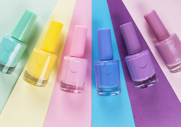 many bottles of nail Polish on colored background, top view - Foto, afbeelding