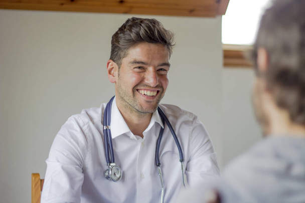 Счастливый молодой врач улыбается в консультации
 - Фото, изображение