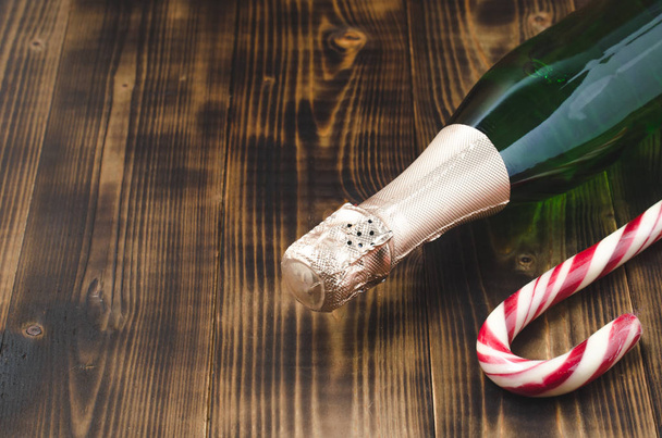 Holiday Bottle of champagne and candy canes over wooden backgrou - Foto, Imagem