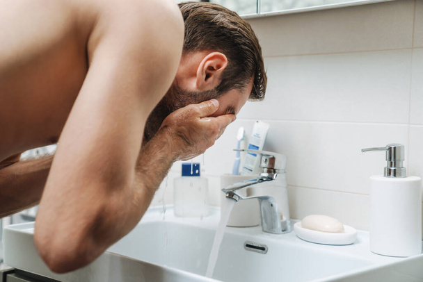 Handsome young shirtless man washing his face - Foto, Bild
