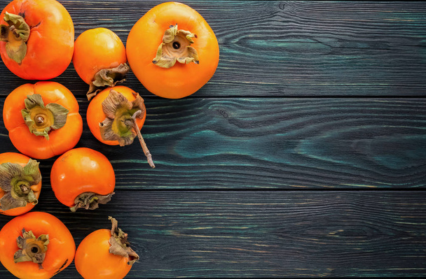 Ripe, orange, juicy persimmons on a wooden old, textured  - Foto, Imagem