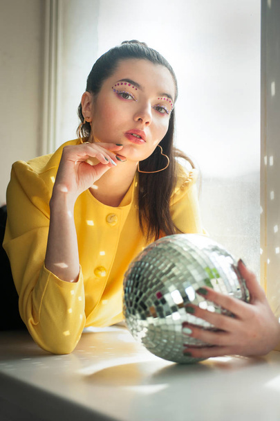 Jeune femme avec maquillage d'épice coloré lumineux et boule disco miroir
 - Photo, image