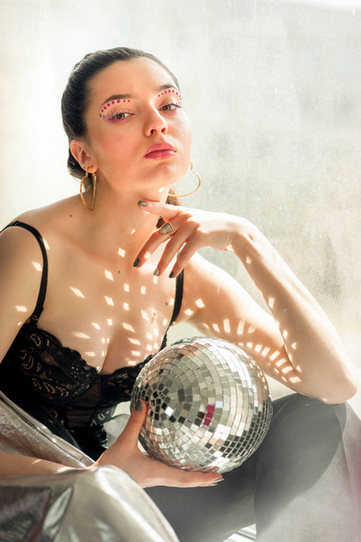 Young woman with bright colorfull spice makeup and Mirror disco ball with shines on shes body. - Photo, Image
