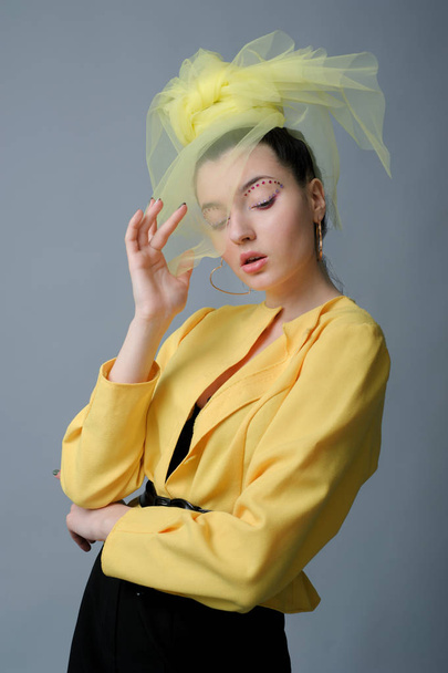 Glamour γυναίκα μόδας με art makeup σέξι σύντομο κομψό κίτρινο φθορά και πέπλο στο κεφάλι της - Φωτογραφία, εικόνα