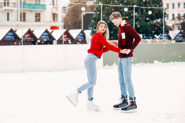 Cute couple in a red sweaters having fun in a ice arena - Foto, Imagem
