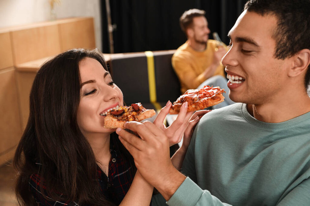 Young couple eating delicious pizza in cafe, closeup - Zdjęcie, obraz