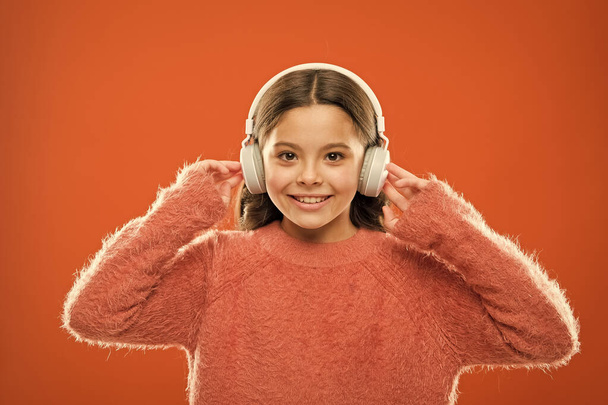 Using bluetooth wireless technology. Little child listening to music in bluetooth stereo earphones. Small girl wearing modern bluetooth headphones. Connecting bluetooth headset to her music player - Фото, изображение