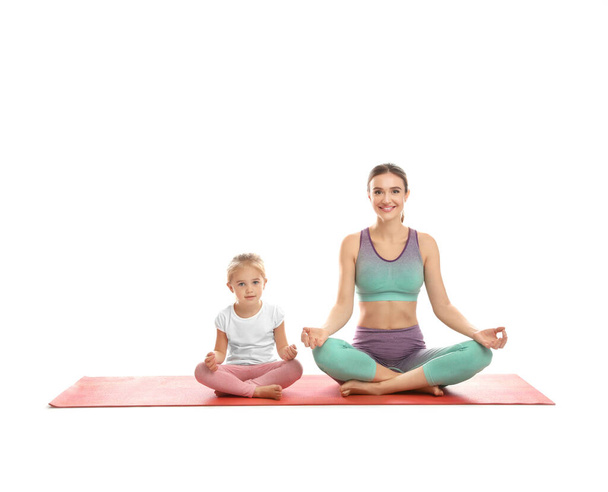 Young woman and her daughter doing exercise isolated on white. Home fitness - Zdjęcie, obraz