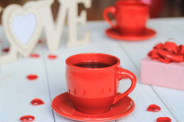 Cup of coffee and gift on blurred background. - Photo, image