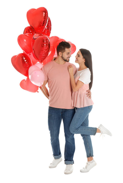 Happy young couple with heart shaped balloons isolated on white. Valentine's day celebration - Valokuva, kuva