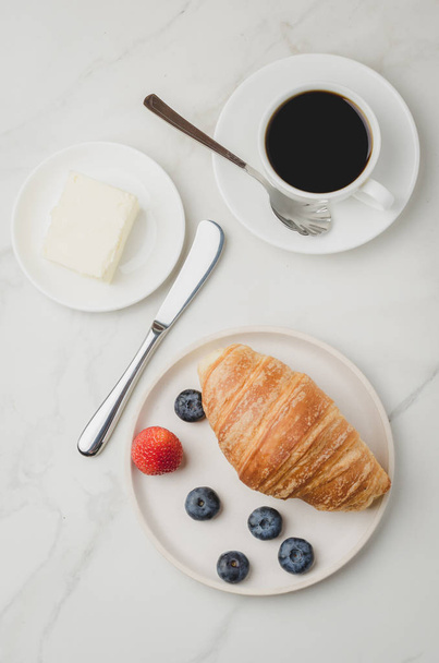Breakfast with croissant, butter knife and fresh berries on a wh - Photo, image