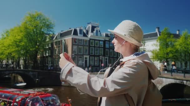A young woman takes a selfie by the canal in Amsterdam - Footage, Video