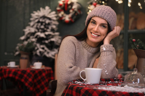 Beautiful woman at table in decorated cafe. Christmas celebration - Foto, imagen