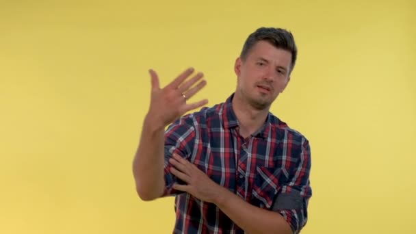 Tall young man deriding somebody, making fun of someone on yellow background. - Imágenes, Vídeo