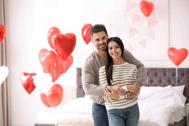 Lovely young couple in bedroom decorated with heart shaped balloons. Valentine's day celebration - Fotografie, Obrázek